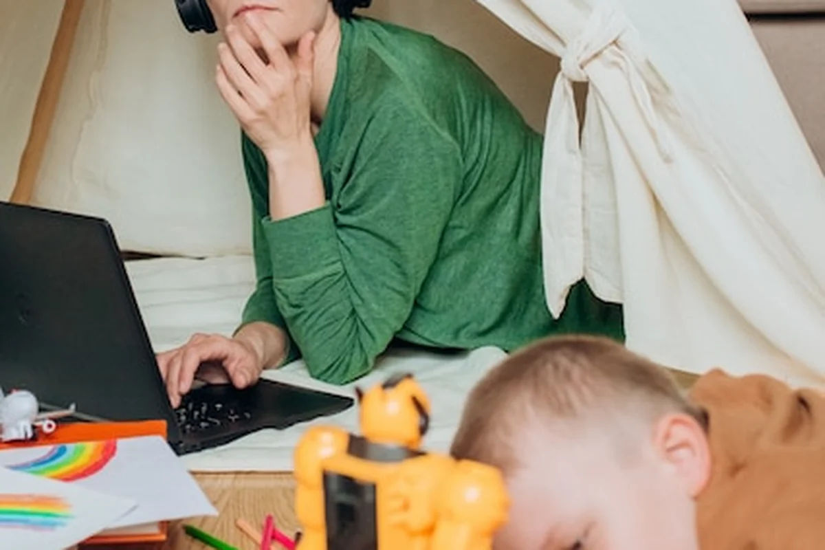 Mama pracuje na laptopie, dziecko gra obok