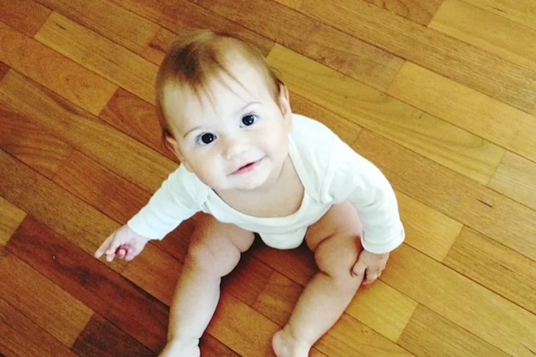 Malutkie dziecko siedzące na drewnianej podłodze
