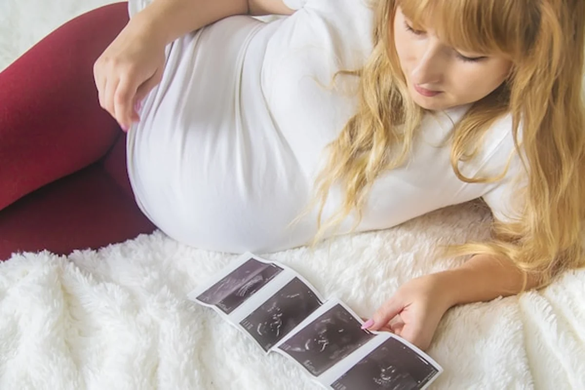 Kobieta w ciąży trzyma migawkę USG