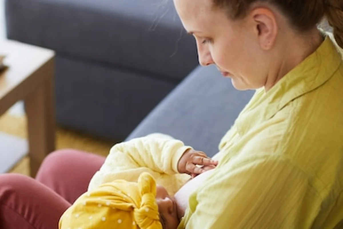 Młoda matka karmi noworodka na kanapie