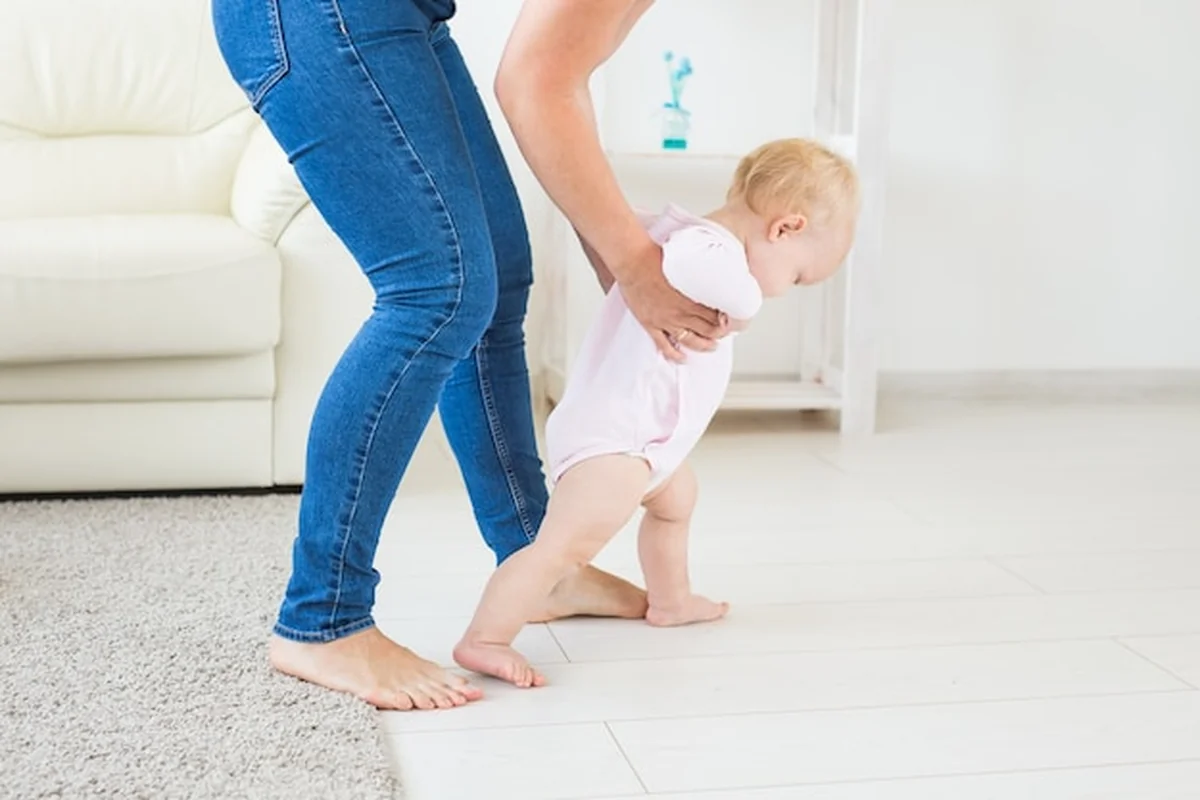Dziewczynka raczkuje przy wsparciu mamy
