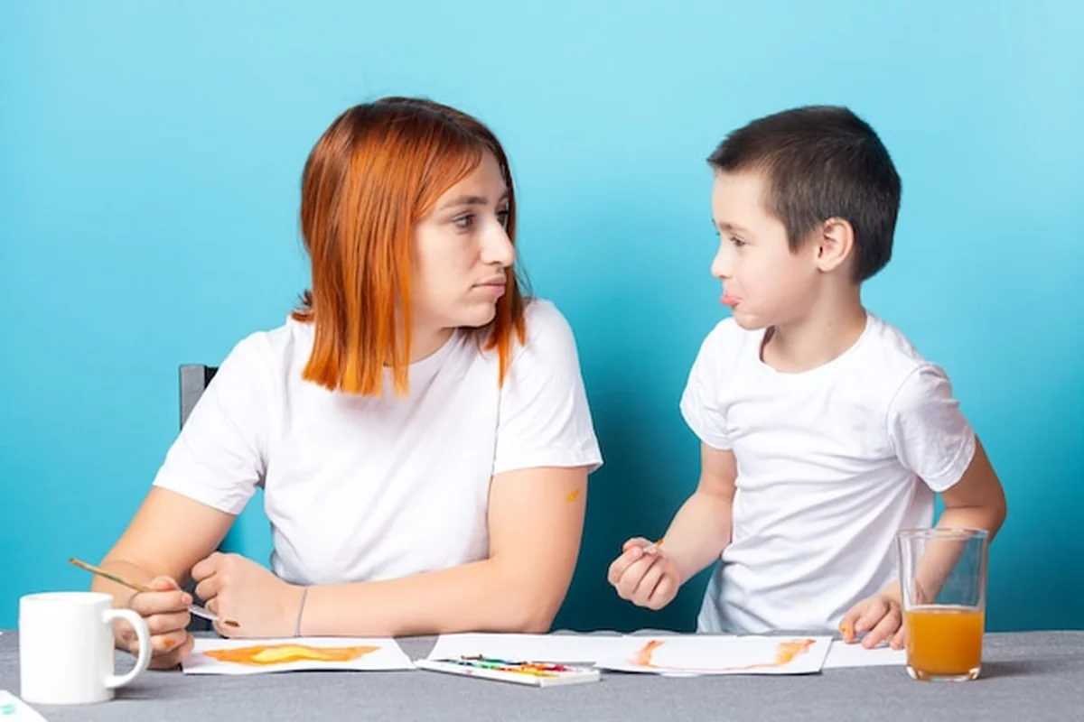 Mama i syn malują akwarelę na niebieskim tle
