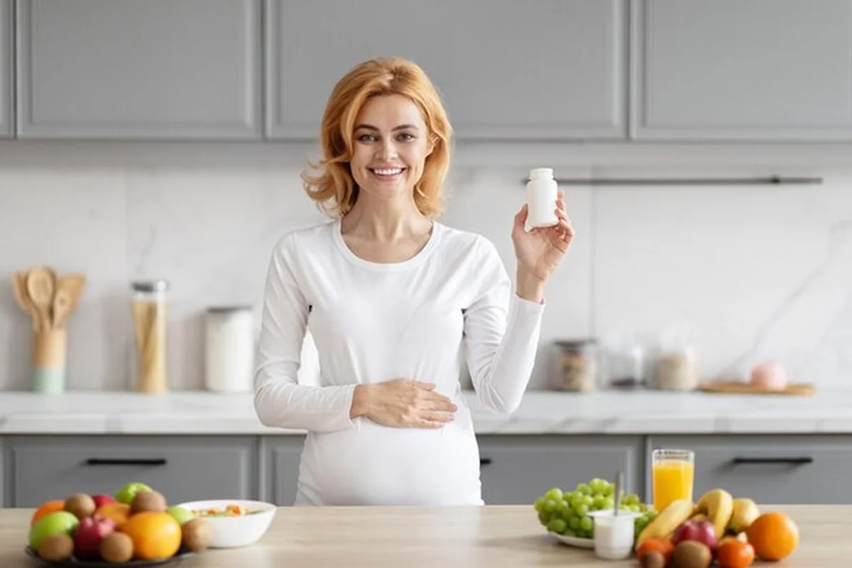 Kobieta w ciąży z suplementami w ręku w kuchni