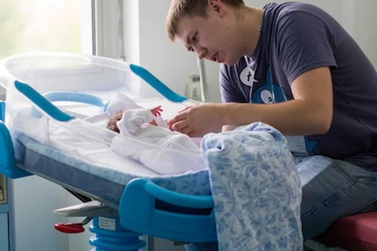 Noworodek w małym łóżeczku patrzący na ojca