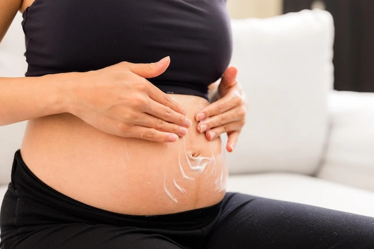 Kobieta w ciąży nakłada krem na brzuch