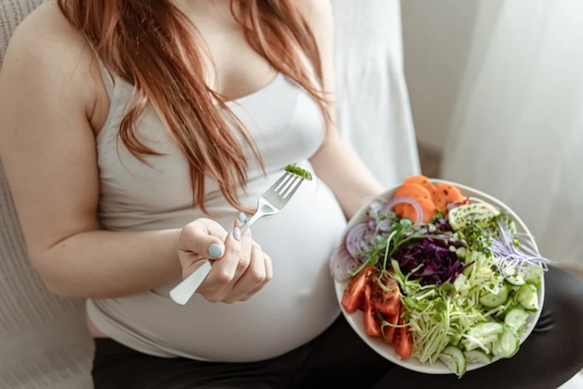 Kobieta w ciąży trzymająca talerz ze świeżą sałatką warzywną