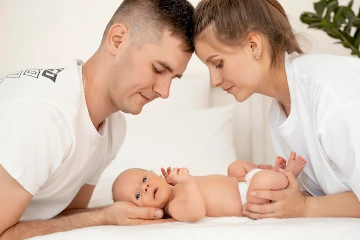 Młodzi rodzice z noworodkiem na łóżku