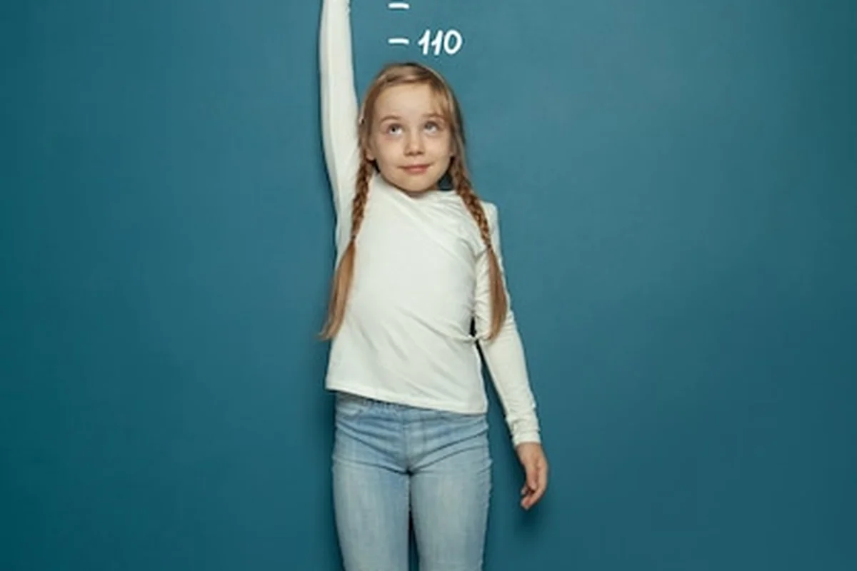 Dziecko mierzące wzrost przy ścianie w domu