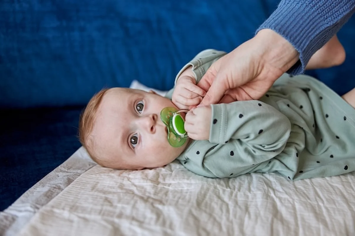 Matka podaje smoczek noworodkowi na kanapie