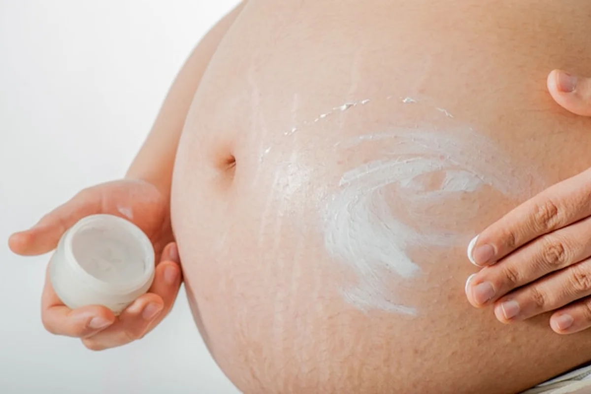 Kobieta w ciąży nakłada krem na brzuch i żołądek