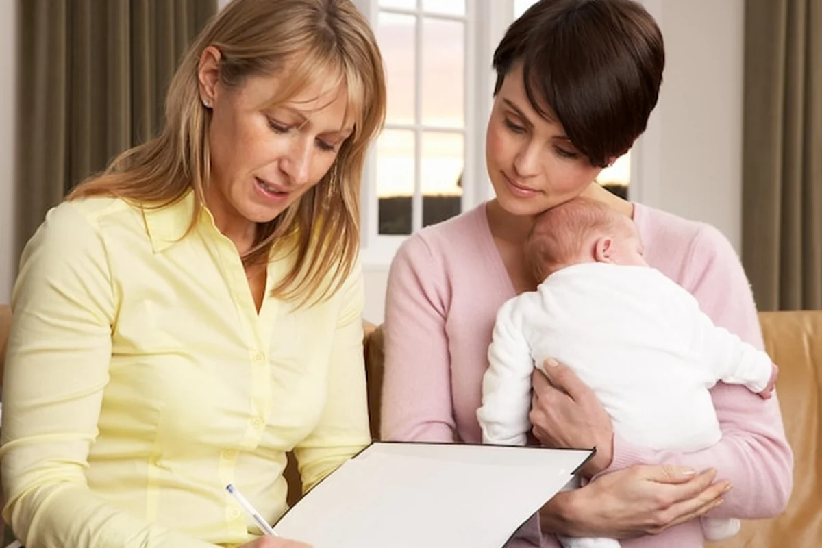 Matka z nowo narodzonym dzieckiem rozmawia z lekarzem w domu